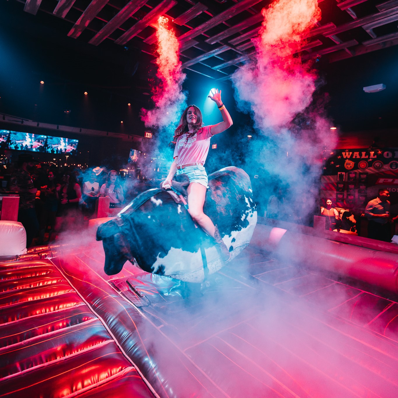 Woman riding a mechanical bull in a bar.